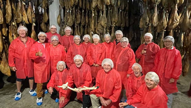 Grupo de turistas con los jamones colgados de fondo