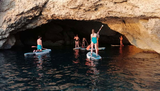 Un gruppo di addentra in una grotta marina sulle tavole
