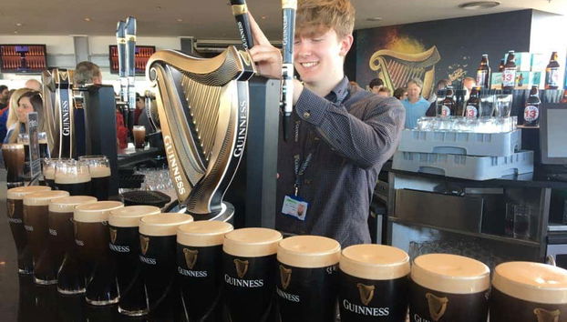 Um garçom servindo um pint de cerveja Guinness