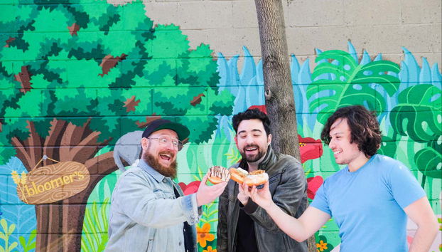 Tres amigos brindando con dónuts