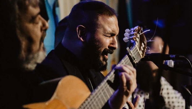 Um músico tocando violão e cantando