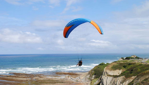 Imagen de dos personas volando en parapente a lo lejos