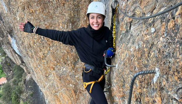 Une jeune femme escaladant la via ferrata