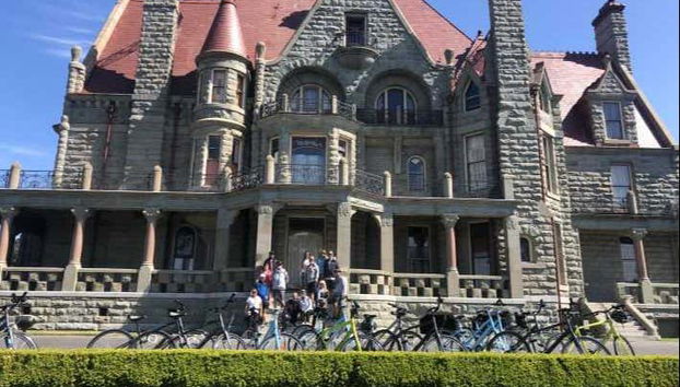 Turistas de bicicleta em frente ao Craigdarroch Castle de Victor