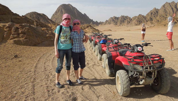 Casal junto dos quadriciclos no deserto