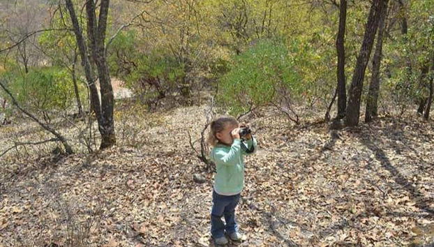 Uma menina apreciando a vista com binóculos prismáticos